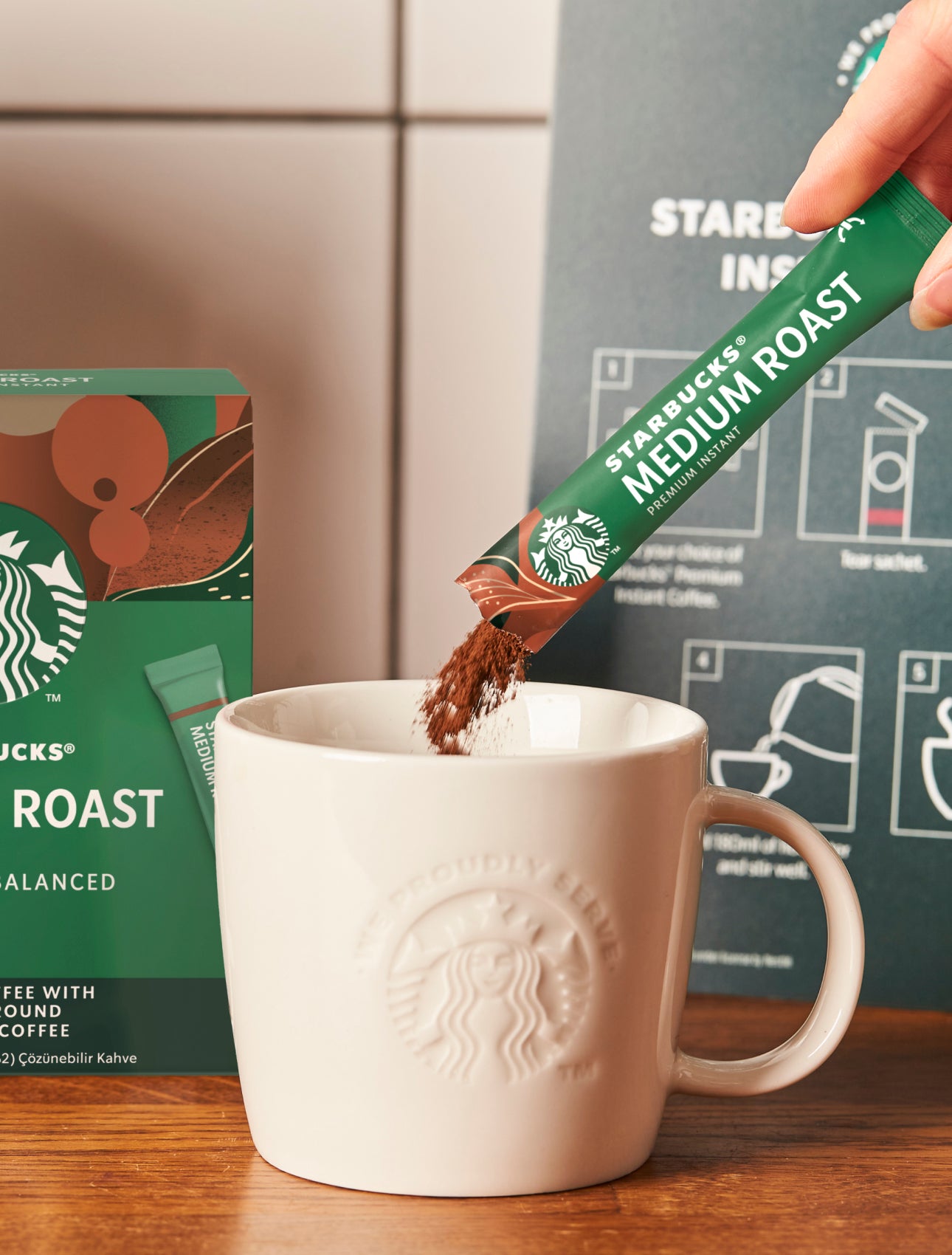 Un pliculeț de cafea Starbucks Premium Instant Medium Roast turnat într-o cană de ceramică We Proudly Serve Starbucks