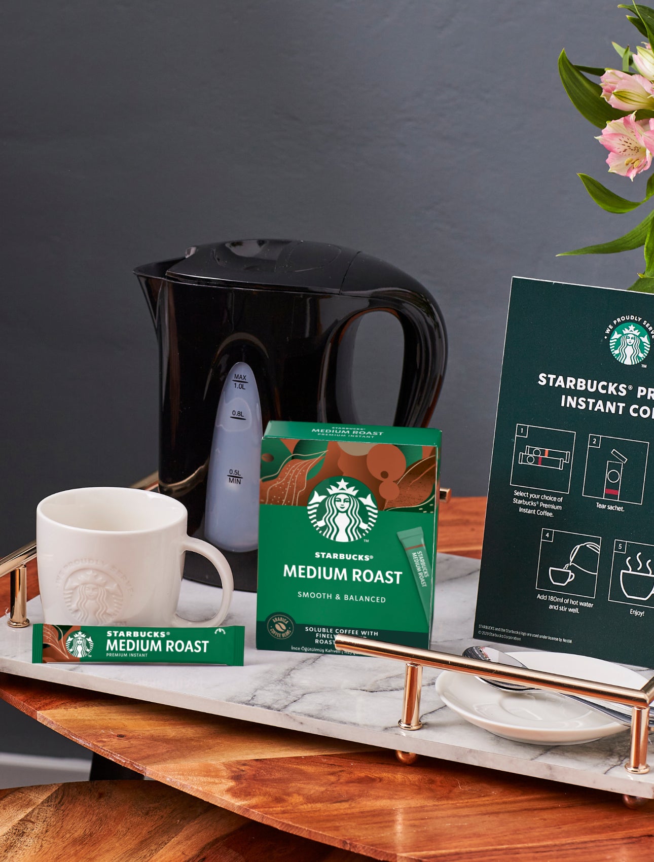 Blat de masă cu o cană We Proudly Serve Starbucks, cafea Starbucks Premium Instant și instrucțiuni de preparare