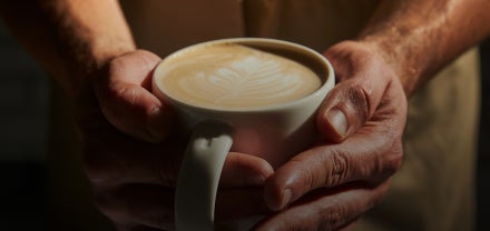 Prim-plan cu mâini care țin o ceașcă de cafea Starbucks
