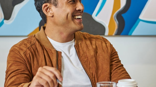 Bărbați așezați la o masă de conferințe ținând în mână cafeaua We Proudly Serve Starbucks